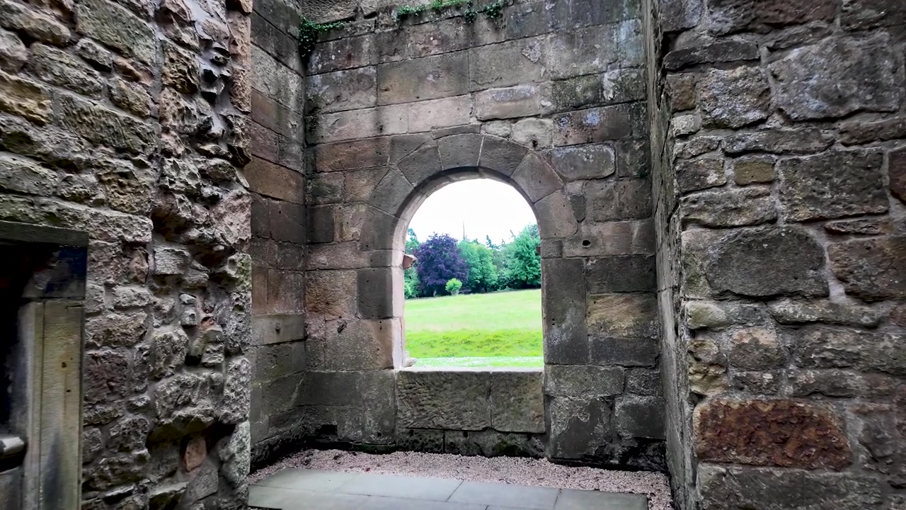 Interior of an ancient stone castle ruin with a view of the green landscape from an arched window. push forward shot