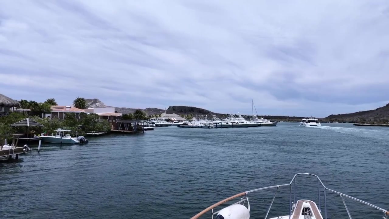 Yacht di lusso che navigano oltre il porto turistico del Curaçao Yacht Club in una giornata nuvolosa. Lungomare panoramico. La vista includeva yacht da pesca sportiva ormeggiati, acque caraibiche calme e una costa tropicale.
