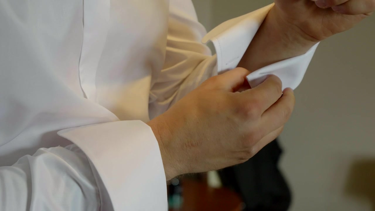 Lo sposo, durante i preparativi del matrimonio, sistema i polsini della camicia e li allaccia con i gemelli