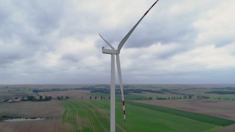 lone tri-blade windmill stop spinning in greenfield against a cloudy sky in kwidzyn, poland - drone shot