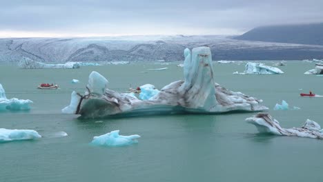 比較小的船只在jokulsarlon的綠色冰川湖水中穿過巨大的冰山