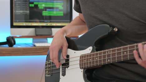 a medium shot of a man playing guitar solos, chords and rhythm with bass in a studio focussing on the hands