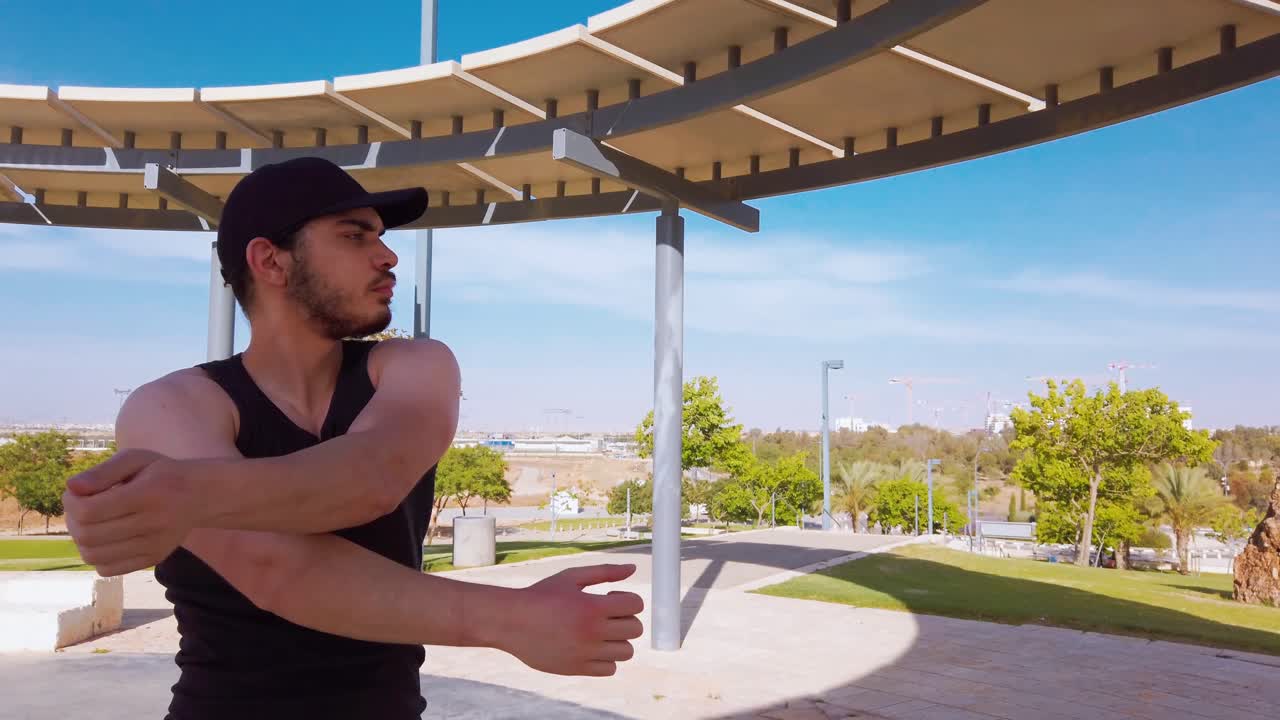 Young men warming up exercises in park. Stretching arms.