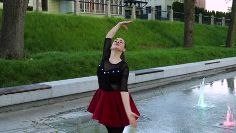 close up on a stunning female dancer dancing in the park next to a fountain