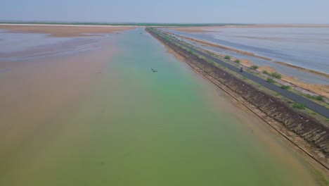 vista cinematográfica de la carretera con lago de agua salada a ambos lados, agua clara en la carretera que conecta khavda con dholavira en kutch, gujarat, india 4k drone