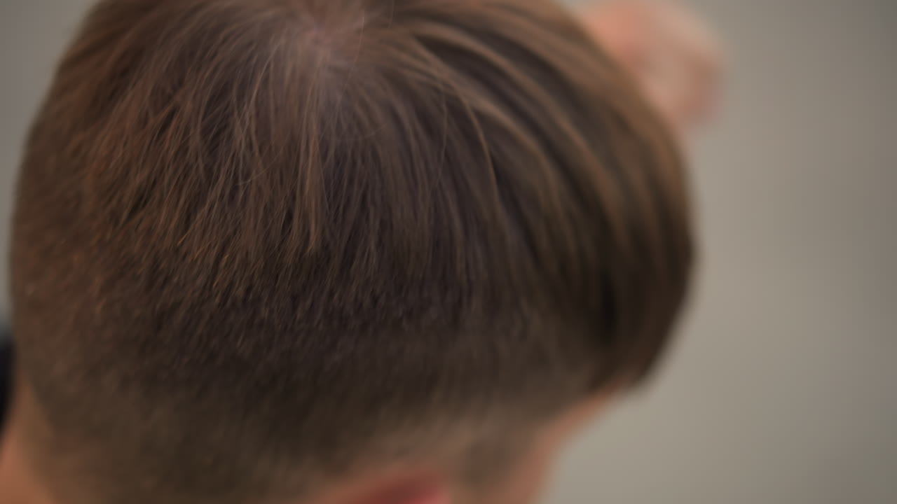 남자가 숱이 적어진 머리카락을 자세히 확인하는 클로즈업, 손가락으로 머리카락을 갈라 뿌리와 모낭을 드러내고, 초조한 마음으로 헤어라인을 점검하는 환자, 미용 및 피부과 테마, 차분한 분위기