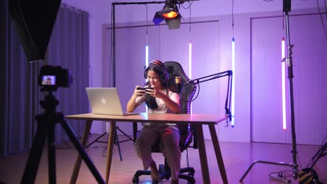 asian kid girl playing video game with mobile phone then celebrating while live stream, professional light equipment