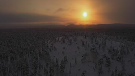 aerial: frosty forested hills, low visibility on a hazy evening in lapland