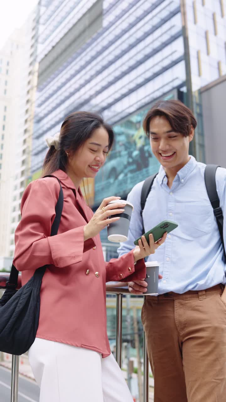 Two people looking at a phone while drinking coffee
