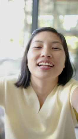 행복한 아시아 여성이 비디오 통화를 하고 이 나는 거실에서 미소 짓고, 느린 동작