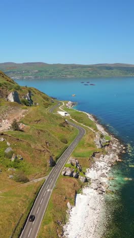 advancing social ratio aerial video of glenarm on the causeway coastal route on a bright and sunny day. filmed in 1080x1920 social ratio, in 60fps and with rec709 color