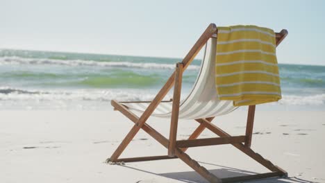 close up of deck chair and towel on beach, in slow motion, with copy space