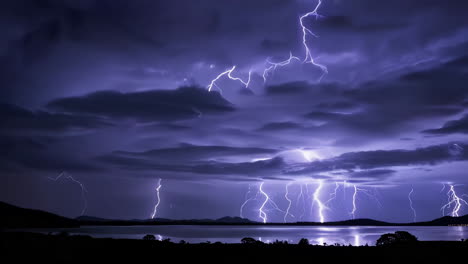 multiple lightning strikes over a dark lake and sky at night