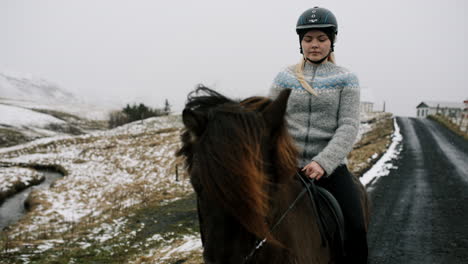 woman horseback riding in snowy icelandic landscape
