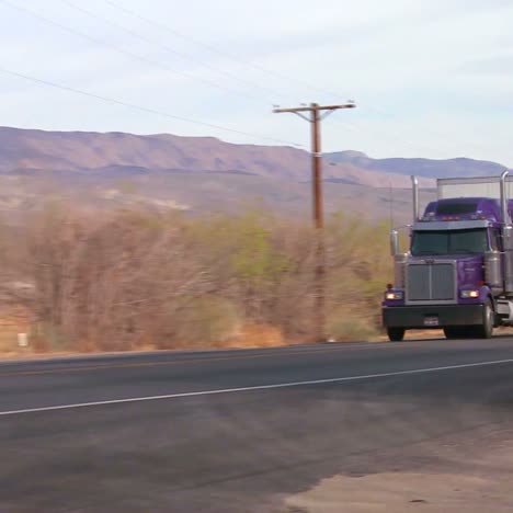 a long distance truck drives on a road through the desert