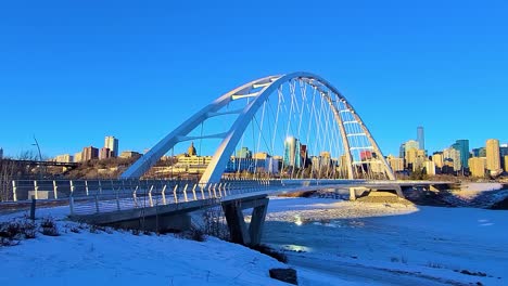 4k bucle perfecto invierno lapso de tiempo crepúsculo blanco moderno walter dale bridge vista de tráfico del norte en un cielo azul claro tarde soleada con el horizonte de la ciudad en el horizonte refkection en el río helado que se derrite