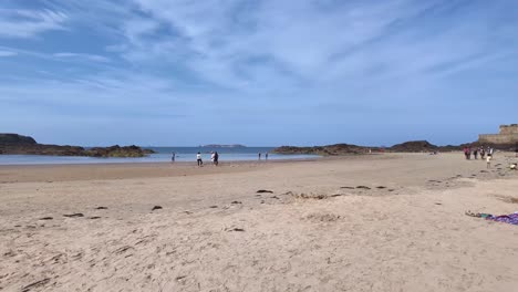sunny sandy beach around fortified old town of saint malo and distant fort national, brittany, france