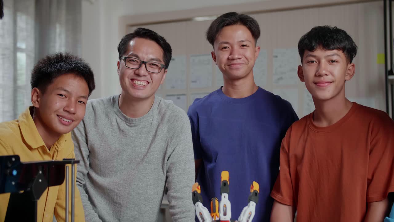 과 3d 프린팅을 가진 아시아 남자와 소년들은 학교에서 사이보그 손에 대해 논의하는 동안 카메라에 미소 짓고 있습니다.