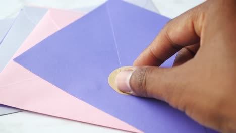 person putting a thank you sticker on an envelope