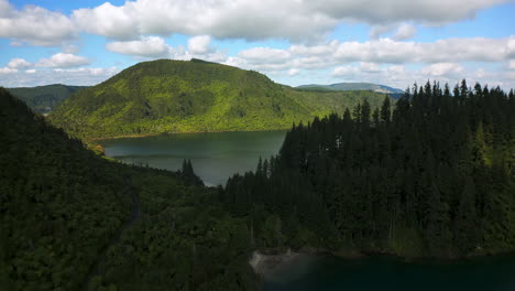 lush forested hills and calm blue lake under a partly cloudy sky in rotorua new zealand