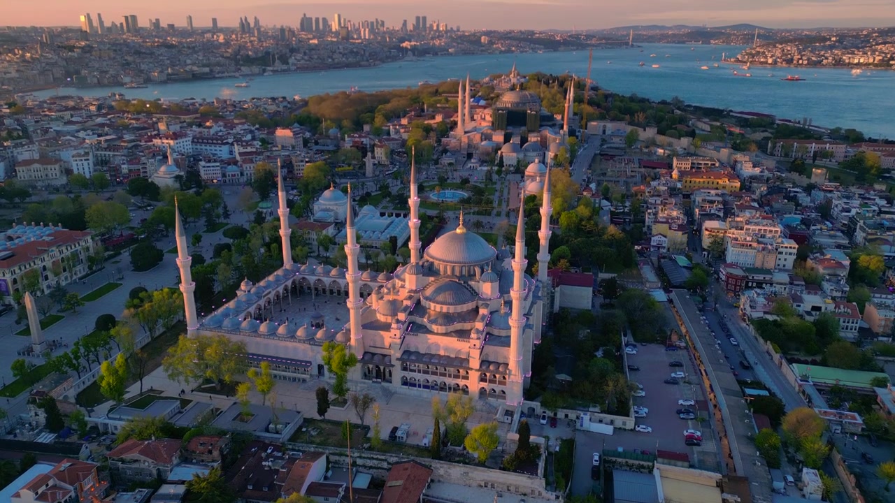 Mezquita Azul con sus minaretes y cúpulas bañadas en luz dorada contra el paisaje urbano de Estambul y el Bósforo. Maravillosa vista aérea, panorama descendente de dron.