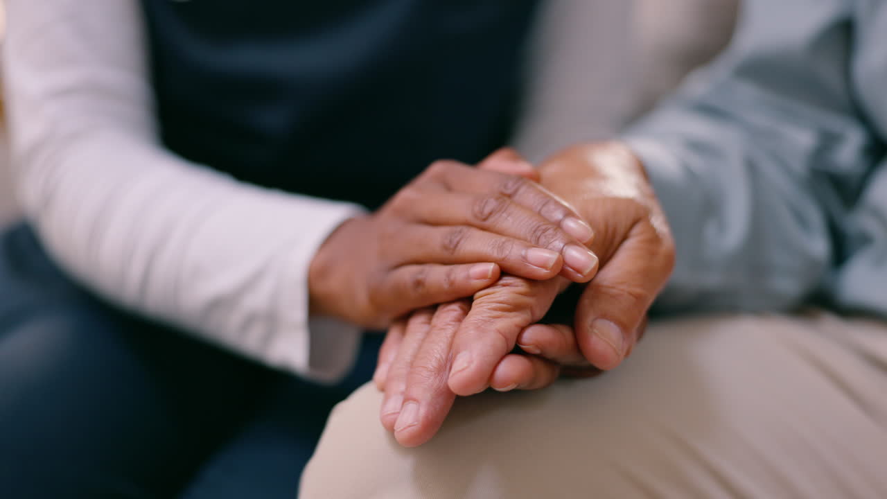 un cuidador que sostiene la mano de una persona mayor