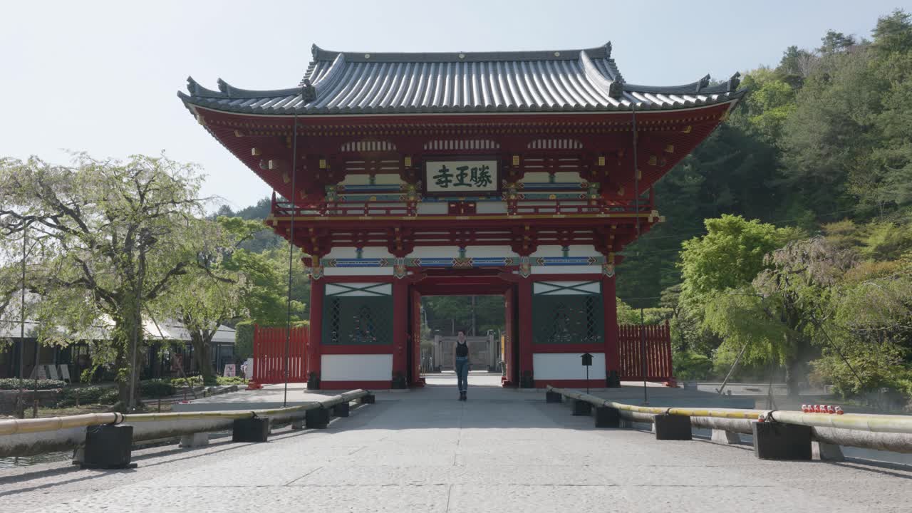 Young caucasian man walking through the entry gate at Katsuoji Temple on a sunny day Osaka, Japan