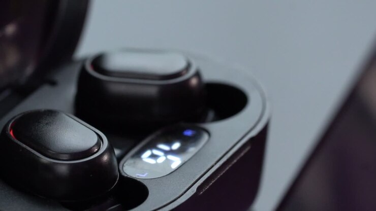 Macro de um par de fones de ouvido sem fio em estojo de carregamento