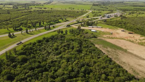 Empty-truck-leaving-paper-mill-factory-surrounded-by-rural-area-of-Uruguay-in-summer---aerial-flight