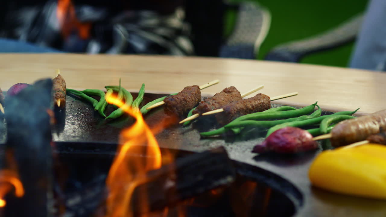 Salsicce al barbecue che grigliano su un barbecue all'aperto. Carne su spiedini che rosola sulla griglia.
