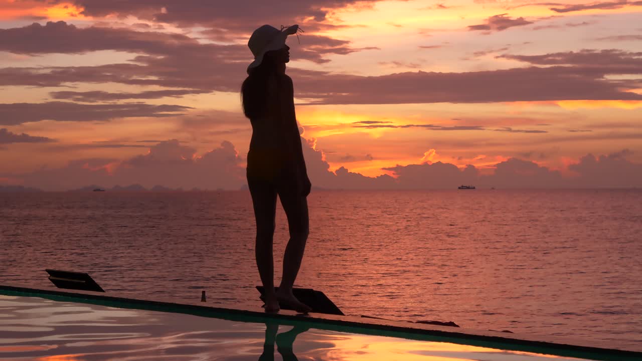 女性は美しい夕暮れの背景、シルエットショットで歩いて投稿しています