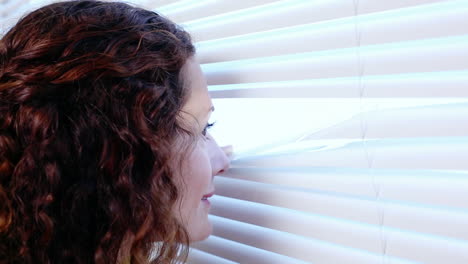 woman peeking through blinds