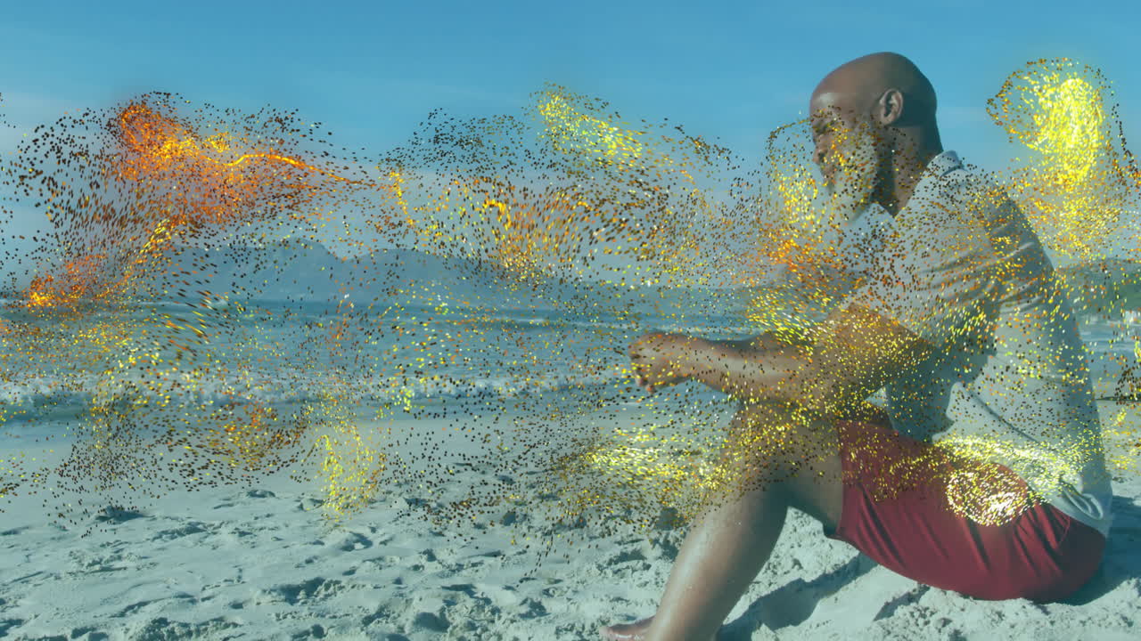 Senior man sitting on beach, watching golden particle animation drifting around, tech theme