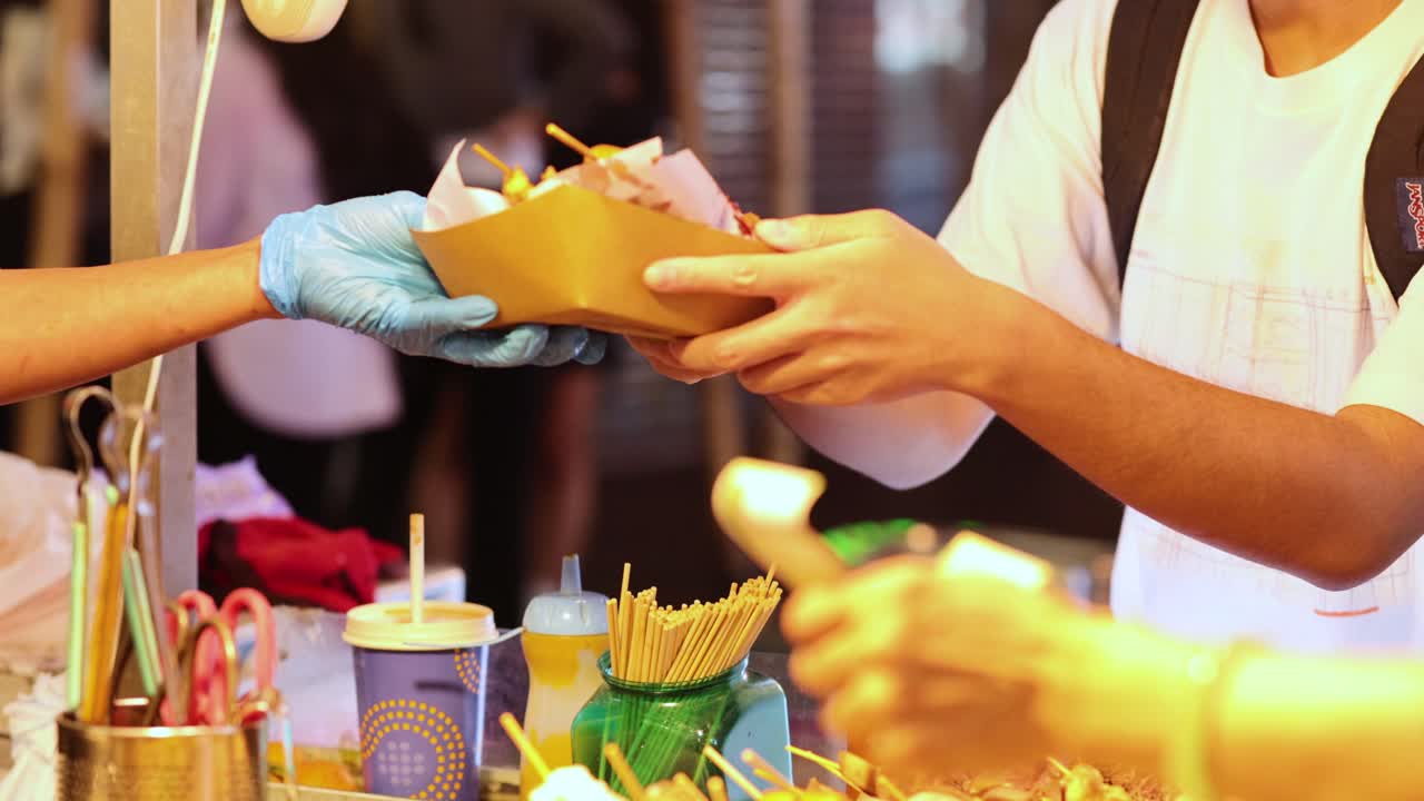 판매자는 야간 시장에서 고객에게 음식을 제공합니다.