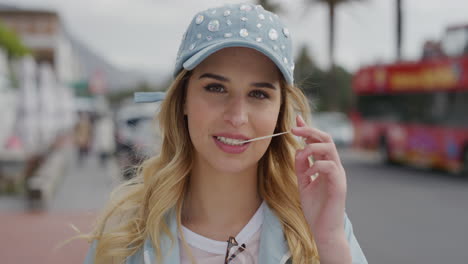 portrait of cute young blonde woman playing with bubblegum looking flirty at camera enjoying urban beachfront vacation on sunny urban street