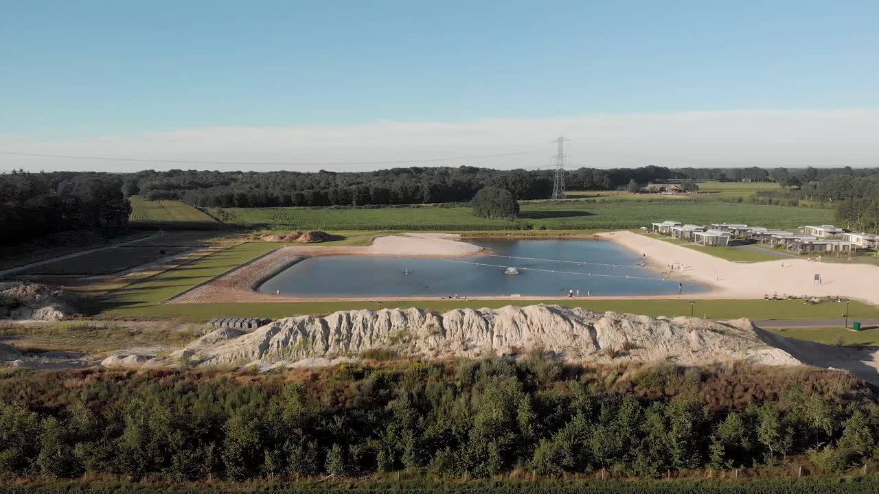 vista aérea del estanque recreativo que desciende y revela un campo de tierras de cultivo de lirios de cabeza reciente con un par de flores antes de la cosecha para la venta de subasta internacional