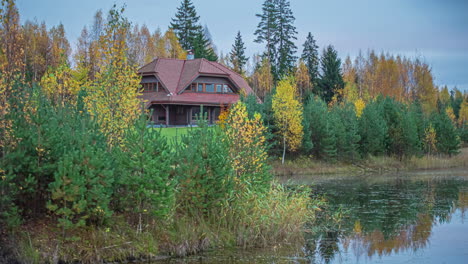 Timelapse-shot-of-a-two-storied-wooden-cottage-in-the-background-with-the-view-of-a-lake-in-the-foreground-during-evening-time