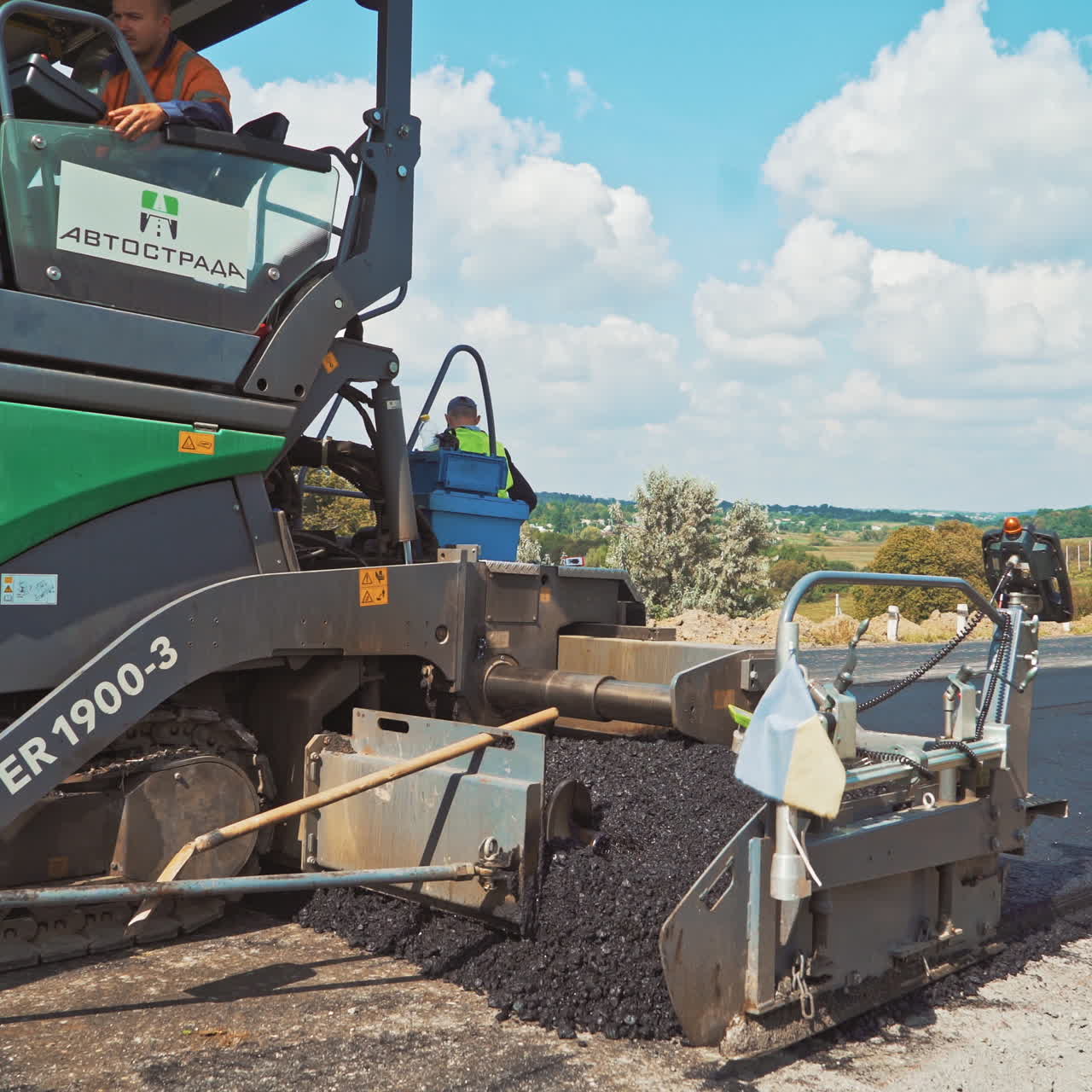 Modern machinery for laying fresh asphalt. Roadworks on a highway. Paver machines pressuring hot asphalt on the road. Road construction works.