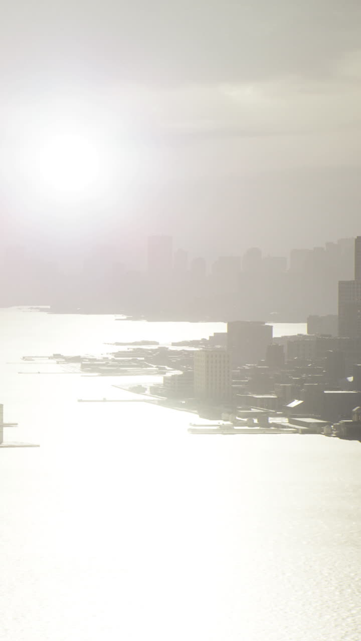 夜明け時に水面に太陽の光が反射する都市のスカイラインの眺め
