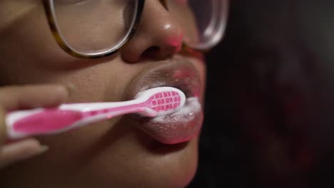 black woman brushing her teeth with a pink brush in the bathroom