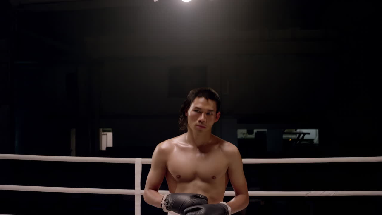 A male boxer stands in a boxing ring, ready for a fight