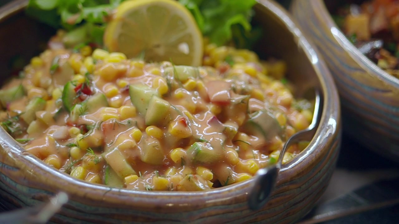 Insalata fresca di mais con cetrioli e condimento cremoso in una ciotola