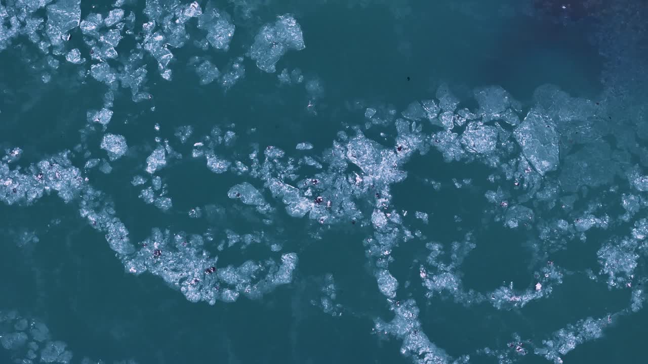 Ice floe swimming in green Icelandic river during daytime in Iceland. Aerial top down shot. Climate change and global warming in Europe. Environmental catastrophe and glacier icebergs.Melting process.