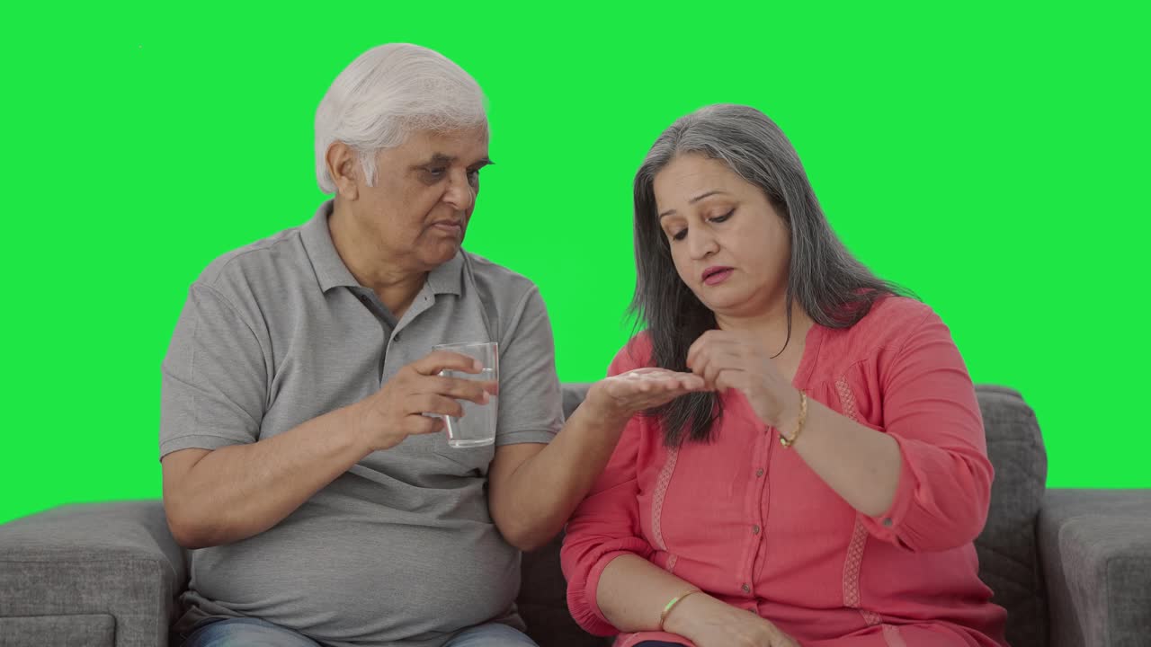 el marido indio dando medicina a su vieja esposa enferma pantalla verde
