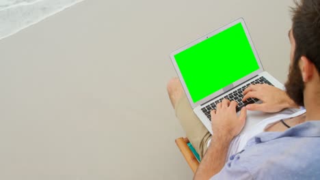 vista de ángulo alto de un hombre usando una computadora portátil en la playa 4k