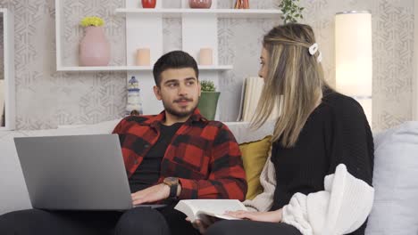 una joven pareja feliz descansa en el sofá de una casa moderna y se sonríen el uno al otro.