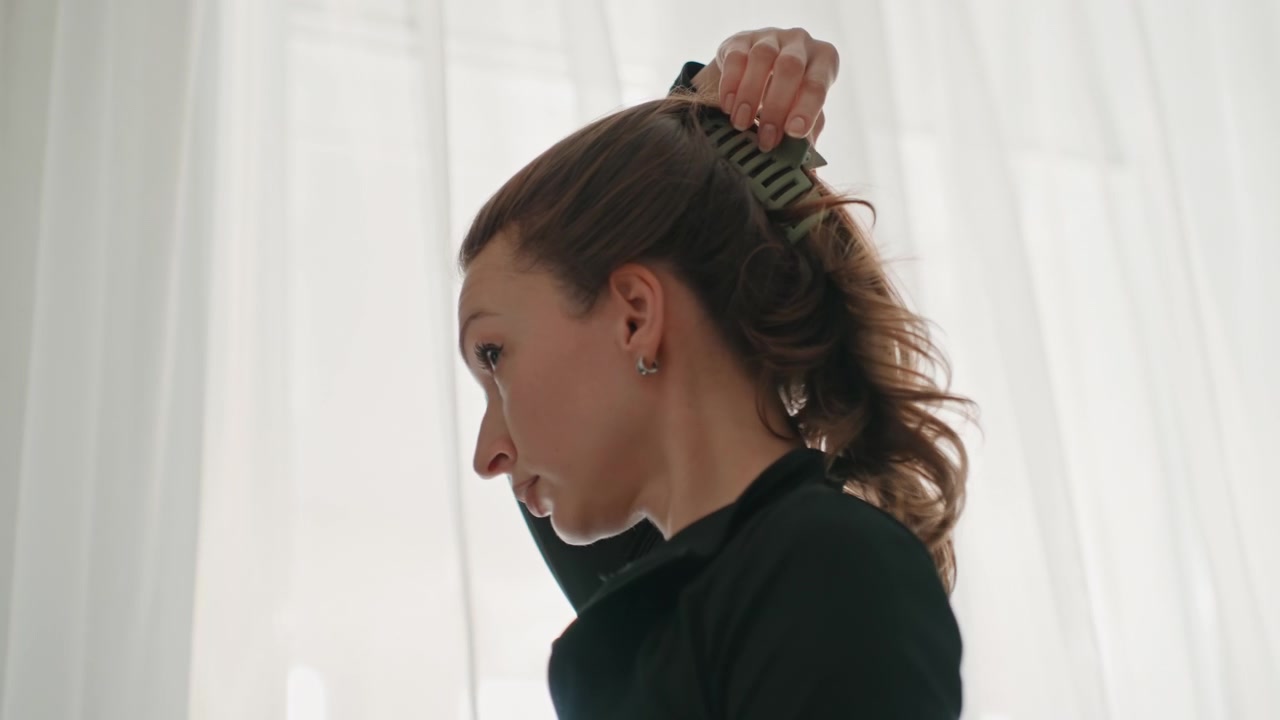 Caucasian woman flipping hair before dance workout at home, dynamic motion captured against sheer curtains, expressive movement and confident gaze, black training top, natural light