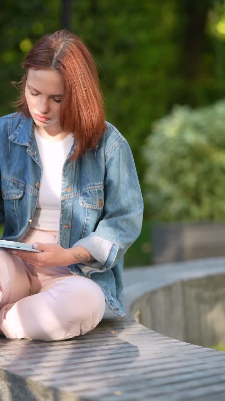 Giovane donna che lavora su un tablet in un parco