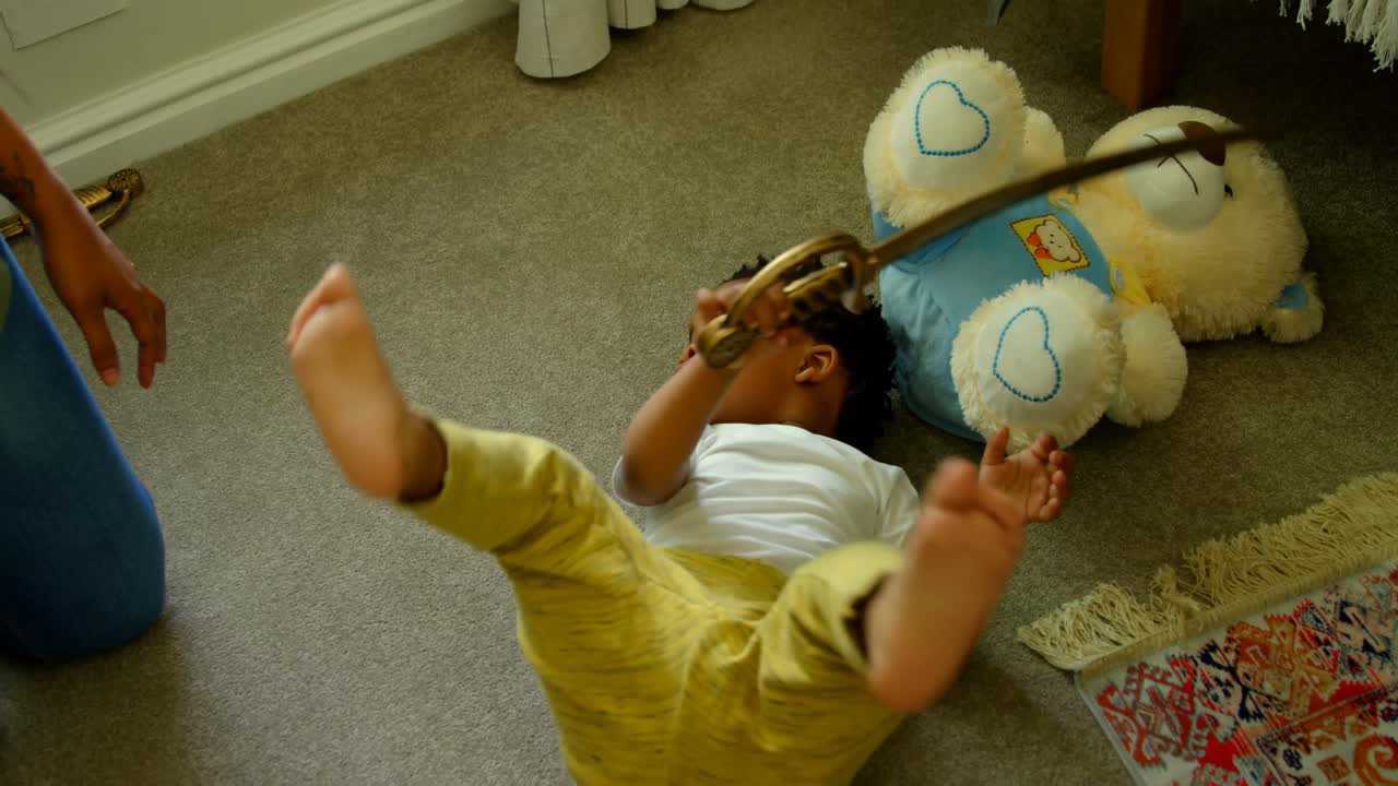 High angle view of cute little black boy playing and lying on floor of comfortable home 4k