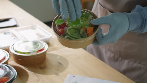 worker applying gluten free sticker on food container